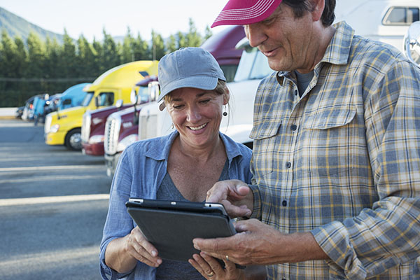 Truck driving couple looking at electronic tablet